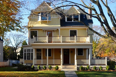 Imagen de fachada de casa amarilla clásica de tamaño medio de tres plantas con revestimiento de madera, tejado a dos aguas y tejado de teja de madera