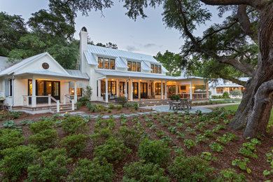 Example of a beach style white two-story brick exterior home design in Charleston with a mixed material roof