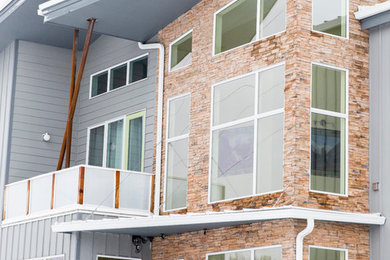 Foto de fachada de casa gris moderna de tamaño medio de dos plantas con revestimiento de vinilo, tejado plano y tejado de metal