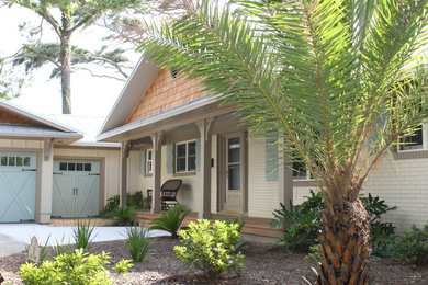 Foto della villa beige tropicale a un piano di medie dimensioni con rivestimento in mattoni, tetto a capanna e copertura in metallo o lamiera
