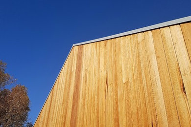 Modelo de fachada de casa contemporánea pequeña de una planta con revestimiento de madera y tejado de metal