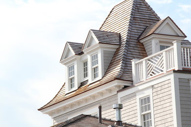 Idée de décoration pour une façade de maison grise tradition en bois avec un toit à quatre pans.