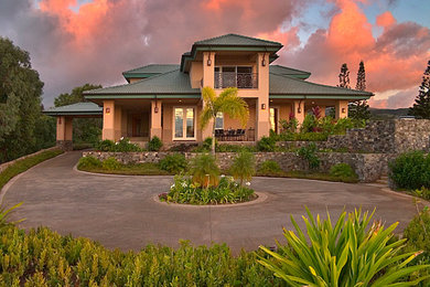 Example of a large island style beige two-story stucco exterior home design in Hawaii with a hip roof