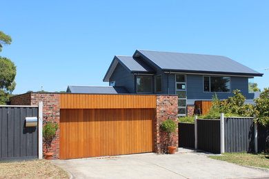 Diseño de fachada de casa gris actual de tamaño medio de dos plantas con revestimiento de madera, tejado a dos aguas y tejado de metal