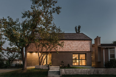 Diseño de fachada de casa actual de tamaño medio de dos plantas con revestimiento de ladrillo y tejado a dos aguas