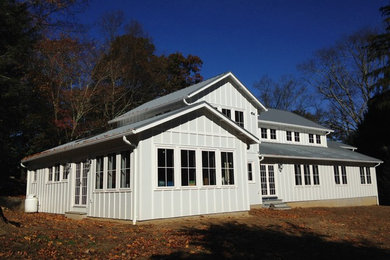 Diseño de fachada de casa blanca de estilo de casa de campo de tamaño medio de dos plantas con revestimiento de aglomerado de cemento, tejado a dos aguas y tejado de metal