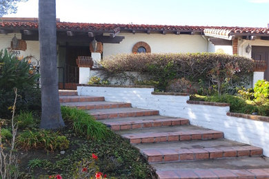 Example of a large tuscan white one-story brick house exterior design in Orange County with a hip roof and a shingle roof