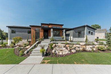 Diseño de fachada de casa gris contemporánea grande de una planta con revestimientos combinados, tejado a dos aguas y tejado de teja de madera