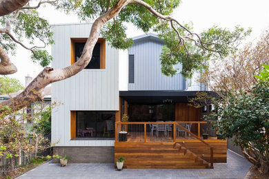 Ejemplo de fachada de casa blanca minimalista de tamaño medio de dos plantas con revestimiento de metal, tejado plano y tejado de metal