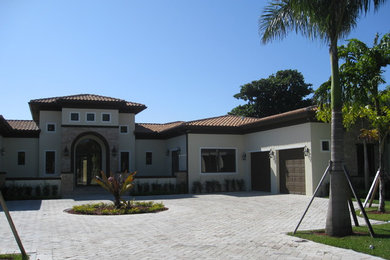 Diseño de fachada de casa beige mediterránea grande de una planta con revestimiento de estuco, tejado a cuatro aguas y tejado de teja de barro