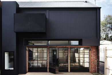 Imagen de fachada negra actual de dos plantas con revestimientos combinados