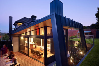 Cette image montre une grande façade de maison métallique et noire design à un étage avec un toit à deux pans.