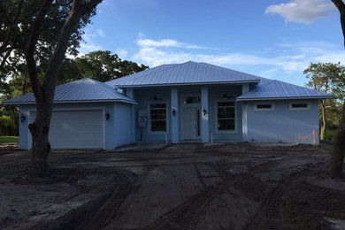 Example of a mid-sized island style blue one-story stucco exterior home design in Miami