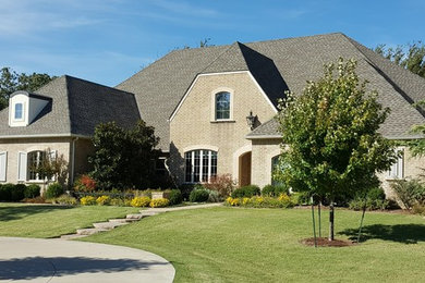 Example of a large classic beige two-story brick exterior home design in Oklahoma City with a hip roof