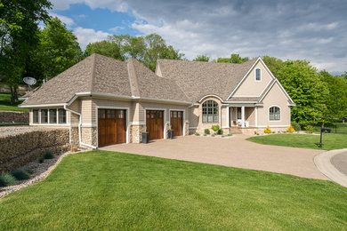 Imagen de fachada de casa beige clásica de tamaño medio de dos plantas con revestimientos combinados, tejado a dos aguas y tejado de teja de madera