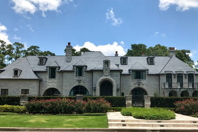 Huge transitional gray two-story stone house exterior photo in Houston with a clipped gable roof