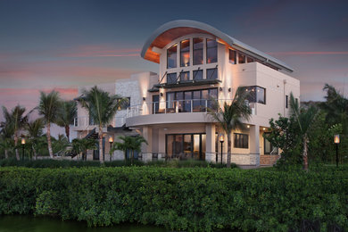 Example of a large trendy beige three-story stucco exterior home design in Miami