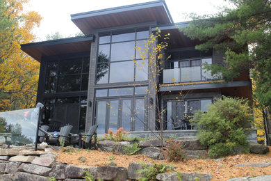 Ejemplo de fachada de casa gris actual grande de dos plantas con revestimientos combinados, tejado plano y tejado de metal