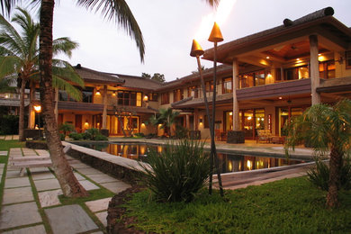 Inspiration for a tropical beige two-story stucco house exterior remodel in Hawaii with a hip roof and a shingle roof