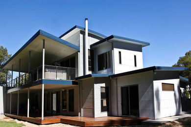 Réalisation d'une façade de maison grise minimaliste à un étage avec un revêtement mixte et un toit en métal.