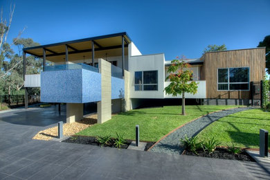 Modelo de fachada de casa marrón contemporánea de tamaño medio a niveles con revestimiento de madera, tejado plano y tejado de metal