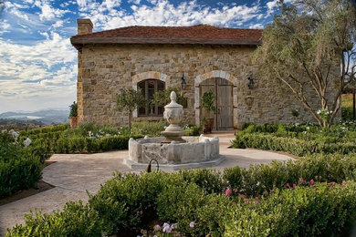 Design ideas for an expansive rustic house exterior in San Diego with stone cladding.