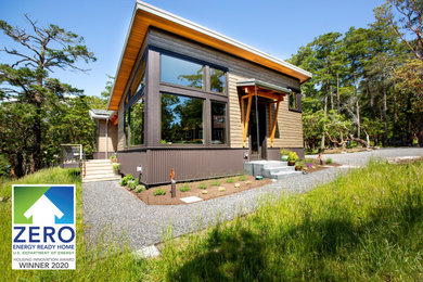 Ejemplo de fachada de casa marrón de tamaño medio de una planta con revestimientos combinados, techo de mariposa y tejado de metal
