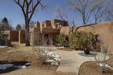 Mid-sized southwestern brown two-story adobe flat roof idea in Albuquerque