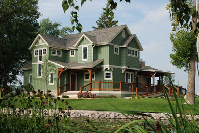 Example of a large arts and crafts green two-story exterior home design in Milwaukee with a shingle roof