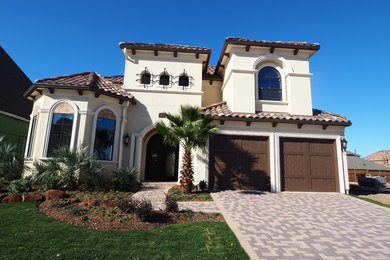 Inspiration for a medium sized and beige mediterranean two floor render house exterior in Dallas with a hip roof.