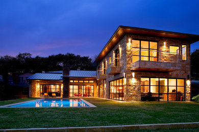 Inspiration for a large contemporary beige two-story stone exterior home remodel in Austin with a hip roof