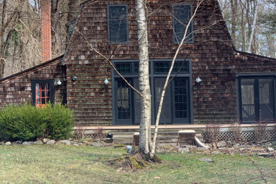 Modelo de fachada de casa marrón bohemia con revestimiento de madera, tejado a doble faldón y techo verde