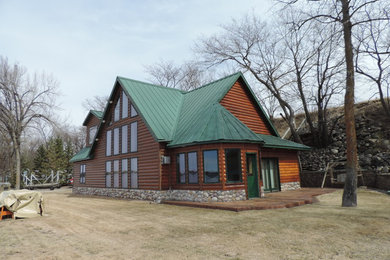 Ejemplo de fachada de casa marrón rural grande de dos plantas con revestimiento de madera y tejado a dos aguas