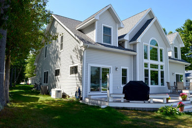На фото: большой, двухэтажный, серый дом в морском стиле с облицовкой из винила и двускатной крышей