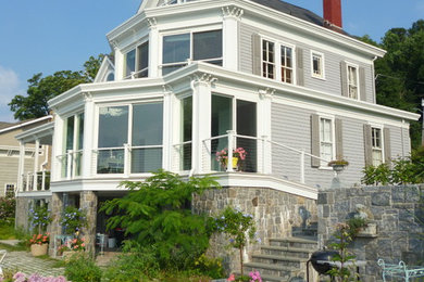 На фото: трехэтажный, деревянный, серый дом среднего размера в классическом стиле с