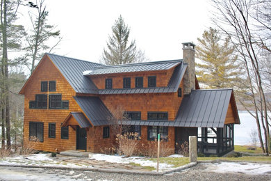 Modelo de fachada de casa marrón rural grande de dos plantas con revestimiento de madera, tejado a dos aguas y tejado de metal