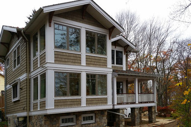 Ejemplo de fachada de casa beige de estilo americano grande de dos plantas con revestimiento de madera, tejado a dos aguas y tejado de teja de madera