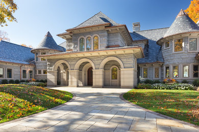Foto della facciata di una casa ampia grigia classica a due piani con rivestimento in pietra e tetto a padiglione