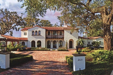 Large tuscan white two-story stucco house exterior photo in Orlando with a shingle roof