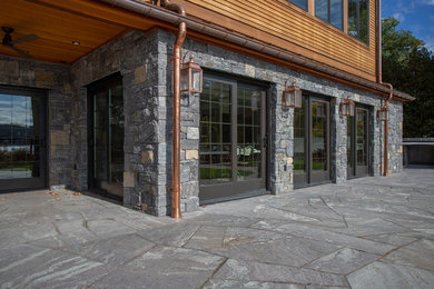 Example of a large mountain style brown two-story stone house exterior design in New York