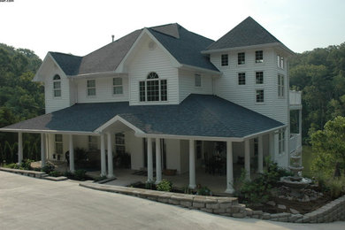 Ejemplo de fachada de casa azul costera grande de tres plantas con revestimiento de vinilo, tejado a cuatro aguas y tejado de teja de madera