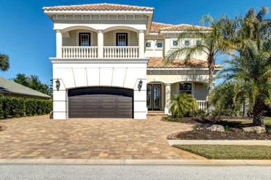 Example of a beach style yellow two-story stucco house exterior design in Orlando with a tile roof