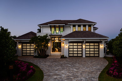 Inspiration for a large coastal white two-story stucco house exterior remodel in Miami with a hip roof and a tile roof