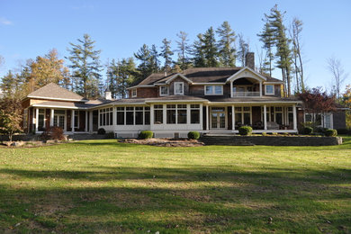 Ejemplo de fachada de casa marrón de estilo americano grande de dos plantas con revestimiento de madera, tejado a cuatro aguas y tejado de teja de madera
