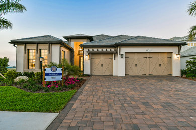 Large modern beige two-story stucco house exterior idea in Other with a tile roof