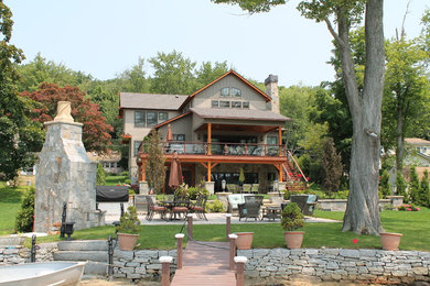 На фото: большой, деревянный, серый частный загородный дом в стиле кантри с разными уровнями, двускатной крышей и крышей из гибкой черепицы с