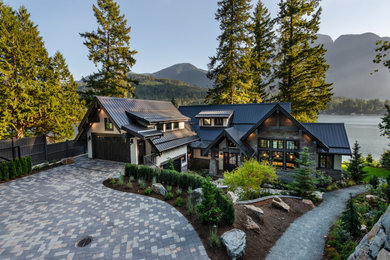 Inspiration for a large rustic gray three-story stone and board and batten exterior home remodel in Vancouver with a metal roof and a black roof