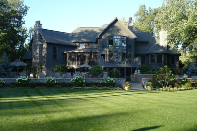 Cette photo montre une très grande façade de maison grise chic en stuc à deux étages et plus avec un toit à quatre pans.