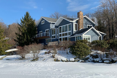 Aménagement d'une grande façade de maison bleue contemporaine à un étage avec un revêtement en vinyle, un toit à deux pans et un toit en shingle.