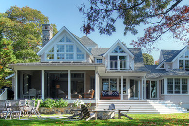 Example of a large beach style gray two-story wood gable roof design in Orange County